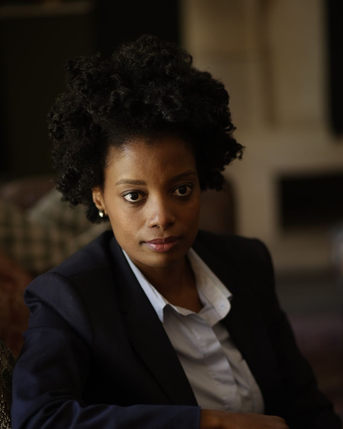 Maud Nale in a navy suit, seated, looking directly at the camera